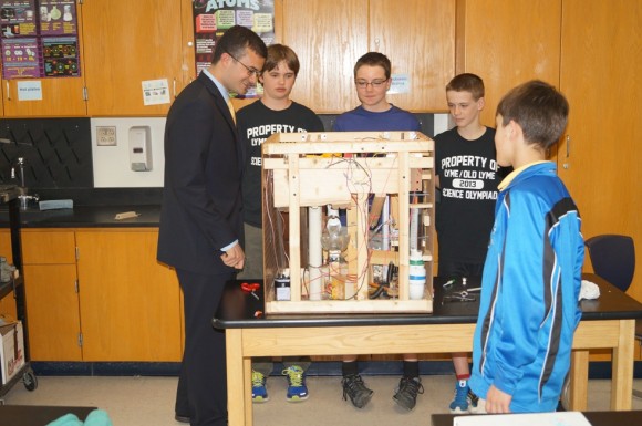 Sen. Art Linares talks with students about their Science Olympiad project, Mission Possible, a complex Rube Goldberg device.  From left to right:  Sen. Linares, builder: Sam Frankel, builder: Ryan Ramella, Ethan Harris, and Sam Fuchs .