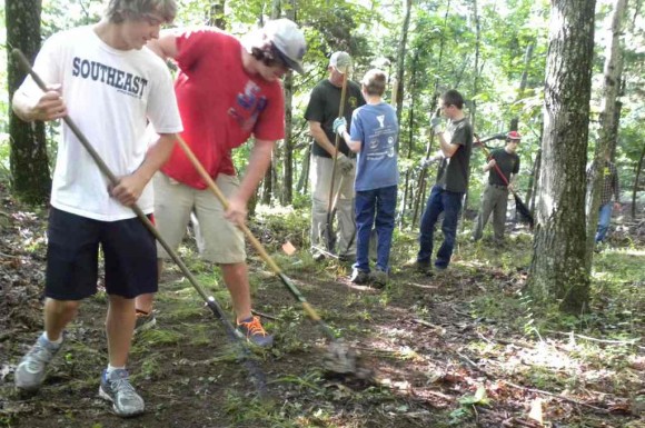 After tree-trimming and brush cutting, the final step of raking the trail nears completion.