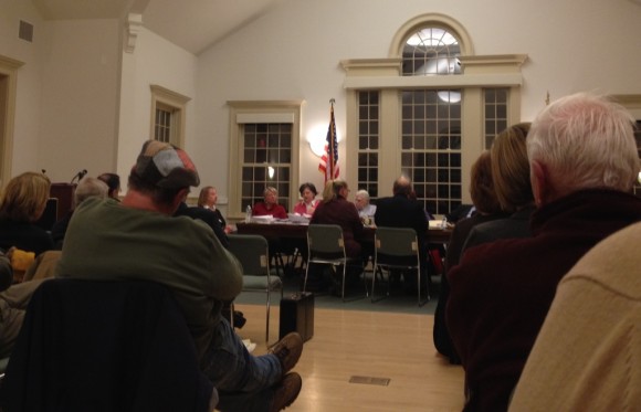 The Chocolate Shell owner, Barbara Crowley, sits with her back to the audience at the table (left) in the town hall's packed meeting room Tuesday evening during the Old Lyme Zoning Board of Appeals meeting.