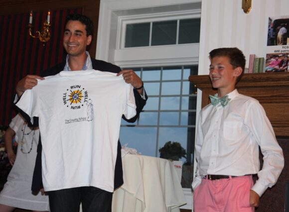 Joseph Coyne presents a Run Well t shirt from the school’s 5K fundraiser to Jordan Rizza, publisher of Coastal Connecticut magazine. The magazine invited Joseph to speak at a recent VIP reception during a Grassy Strip Music Series concert, where The Country School’s well project was the featured nonprofit.