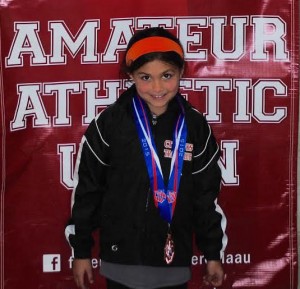 A smiling Zoe Eastman-Grossel proudly wears her Junior Olympics medal.