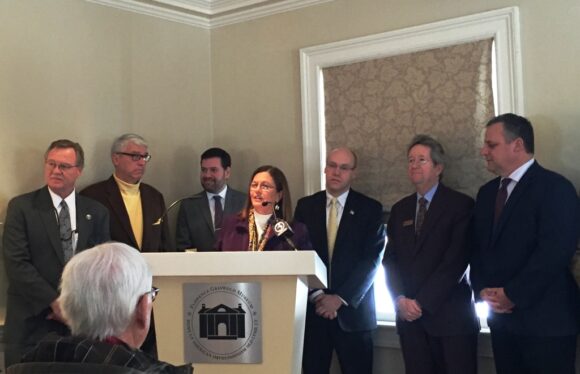 Old Lyme First Selectwoman Bonnie Reemsnyder stands at the podium at Wednesday's press conference at the Florence Griswold Museum. State officials and some of the signatories of a letter to the FRA denouncing Alternative 1 stand around her.