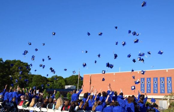 Celebrating receipt of their High School Diplomas in traditional fashion, the Class of 2016 tosses their hats high. Photo by K. StGermain.