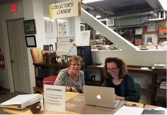 BookCellar Co-managers Ann de Selding (right) and Claudia Condon prepare books for the BookCellar’s upcoming Holiday Sale.